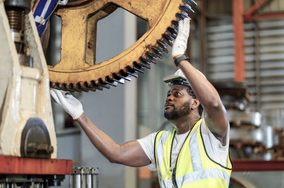 Factory worker inspecting large industrial gear