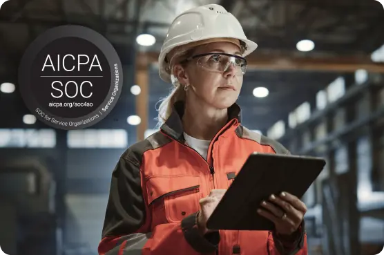 Engineer in safety gear using tablet with AICPA SOC certification badge